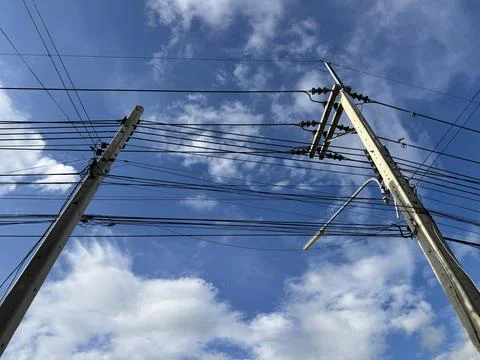 Low angle view of concrete utility poles and overhead power lines. Stock Photos
