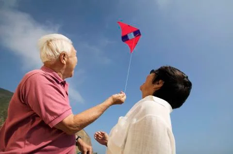 Low Angle View Of A Couple Flying Kite Stock Photos