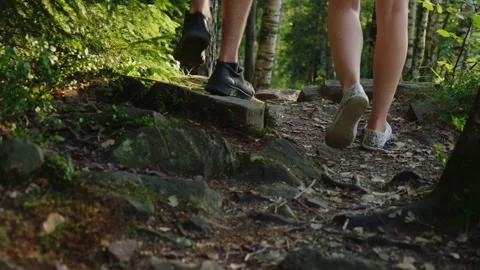 Low angle view of couple legs hiking on rocky forest path during sunset lig.. Vídeos de archivo 334996693