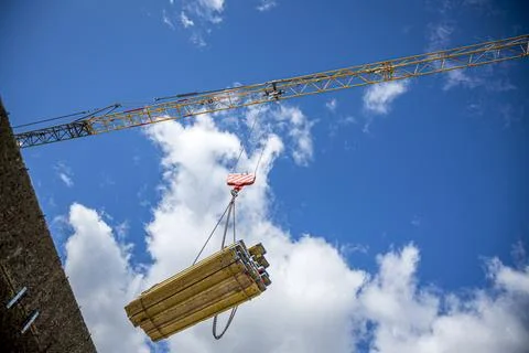 Low angle view of crane carrying construction materials to a construction site. 스톡 사진