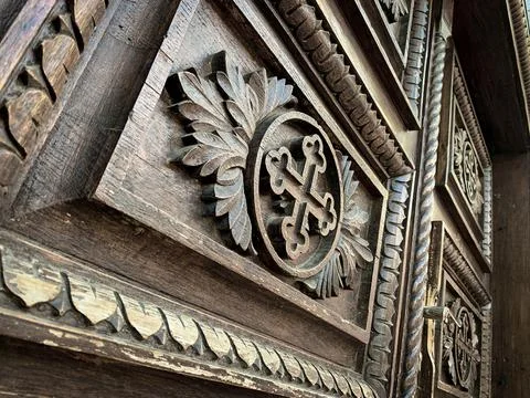Low angle view of cross symbol with ornaments carved on old wooden door  Stock Photos