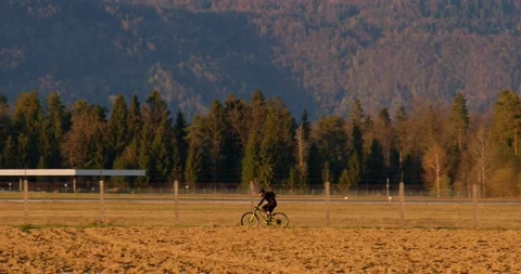 Low angle view of cyclist riding a bike on dirt countryside road Stock Footage 188521876
