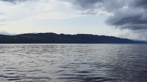 A low angle view of a dark lake and mountains in the distance. Stock Footage 112681885