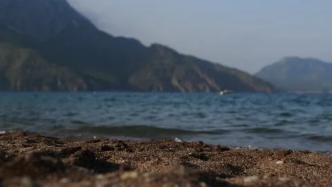 Low angle view on dark sandy beach with sea and mountains view Stock Footage 233679793