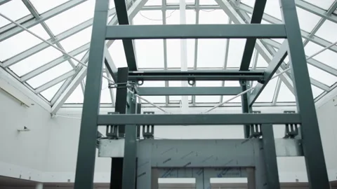 Low-angle view of dark steel framework and bolted guide rail beneath glass Stock Footage 348263477