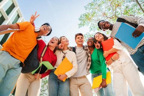 Low angle view of a diverse group of students smiling together, holding not.. Stock Photos