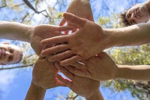 Low angle view of diverse people stacking hands together outdoors symbolizi.. Stock Photos