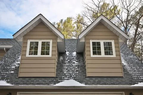Low Angle View of Dormers Above a Garage in a Home with Beige Gray Wood Siding Stock Photos