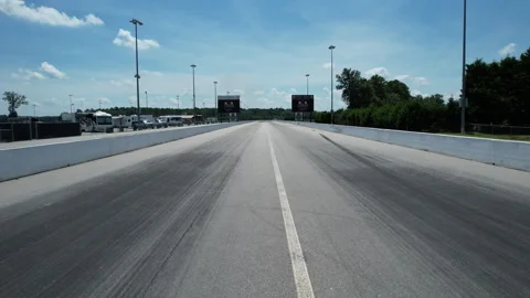 Low angle view down an empty drag strip lined with trees leading to a distant Stock Footage 346175394