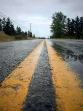 Low angle view down the middle of a road, two yellow lines Stock Photos