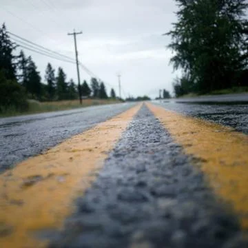 Low angle view down the middle of a road, two yellow lines Stock Photos