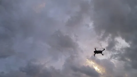 Low angle view of drone entering frame and hovering against clouds Stock Footage 346954274