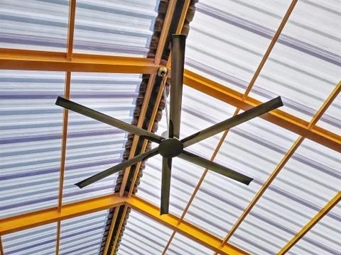 Low Angle View of Electric Ceiling Fan Under Yellow Roof Structure Foto stock