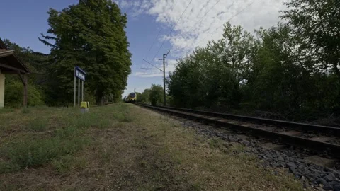 Low-angle view of an electric passenger train passing a small countryside Stock Footage 345336384