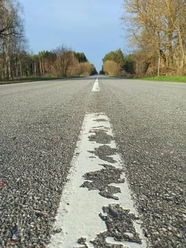 Low angle view of empty asphalt road with worn white dividing line Stock Photos