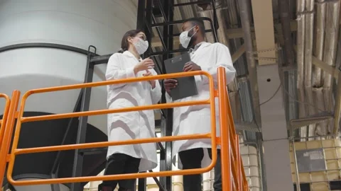 Low angle view of engineers wearing lab coat standing near machines working at Stock-Footage 143962008