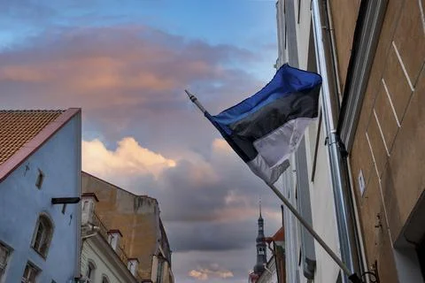 Low angle view of Estonian flag waving against buildings in town during sunset Stock Photos