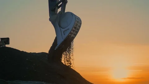 Low angle view of excavator flipping the bucket with soil at sunset Stock Footage 225093415