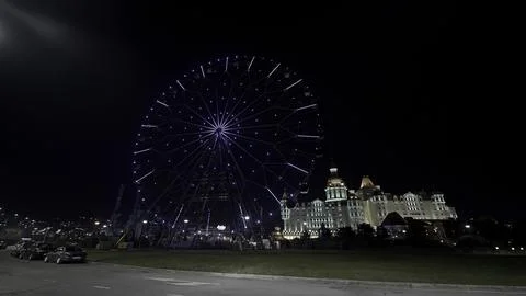 Low angle view of the ferris wheel in front of a castle. Action. Summer evening 写真素材