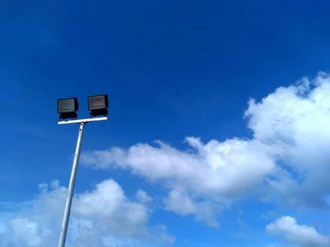 Low angle view of flood lamp against sky and clouds Stock Photos