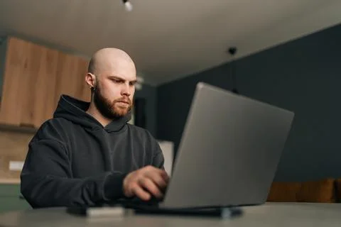 Low-angle view of focused programmer wearing dark hoodie typing code on laptop Stock Photos