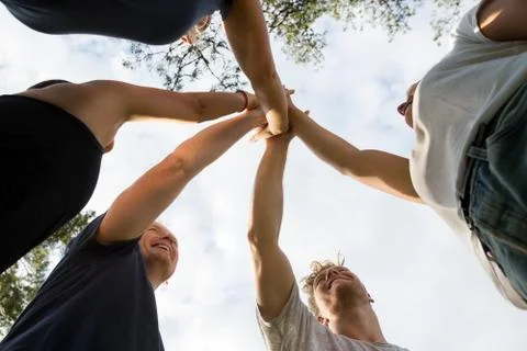 Low Angle View Of Friends Stacking Hands Against Sky Stock Photos