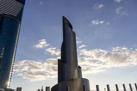 Low angle view of a futuristic twisting metal skyscraper next to a modern b.. Stock Photos