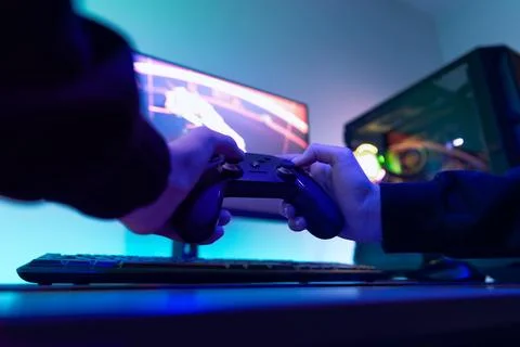 Low angle view of gamer holding controller in front of large monitor displa.. Stock Photos