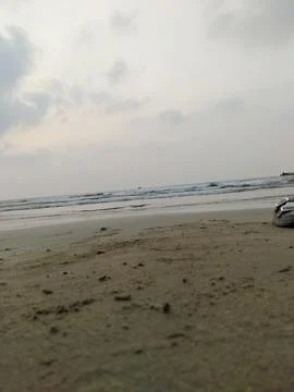 Low angle view of gentle ocean waves reaching a sandy shore under an overca.. Stock Photos