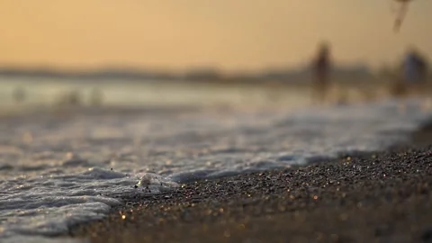 Low angle view of gentle sea waves washing onto pebble beach at golden hour Stock Footage 335763770