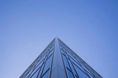 Low angle view of glass facade of tall office building against clear blue sky Stock Photos