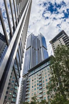 Low angle view of glass skyscraper and surrounding towers Stock Photos