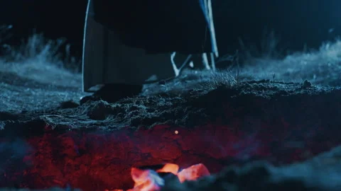 Low-angle view of glowing embers and small blue orange flames beneath charred Stock Footage 345663478