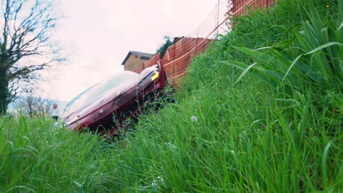 Low angle view from the grass on dirty destructed sport car inside the ditch Stock Footage 318230479