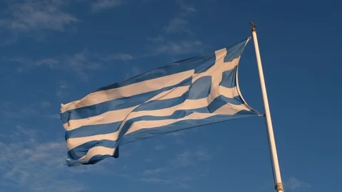 Low angle view of Greek flag on flagpole fluttering in the wind against blue sky Video stock 122474922