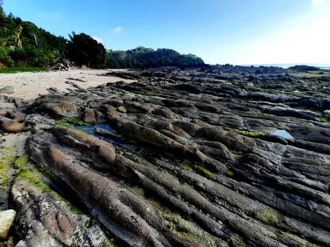 Low angle view from grey rock stones with striped pattern at a rocky sand bea Foto stock