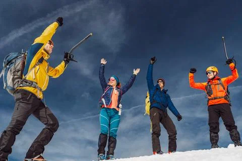 Low angle view, group of hikers jumping in the air when reaching the top of the Stock Photos