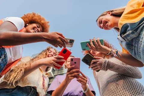 Low angle view of a group of smiling multiracial teenage women addicted to Stock Photos