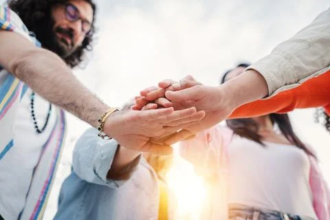 Low angle view of group of young people stacking hands together, collaborating Stock Photos