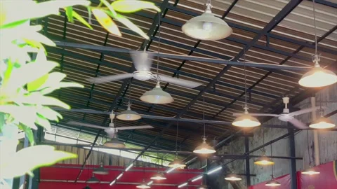 Low angle view of hanging lamps and spinning ceiling fans under the roof Stockbeeldmateriaal 334949832