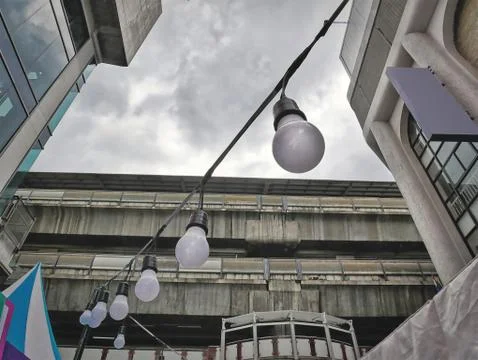 Low Angle View of Hanging Light Bulbs Against Cloudy Sky Foto stock