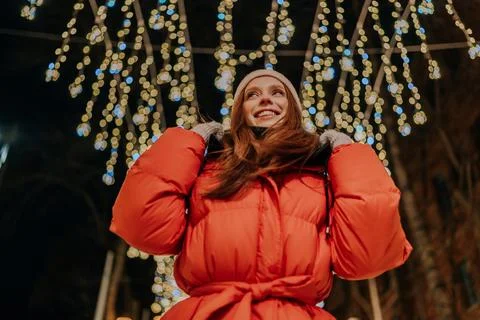 Low-angle view of happy young woman in warm hat and winter jacket standing Stock Photos