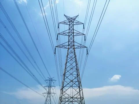 Low Angle View of High Voltage Tower and Power Lines Against Blue Cloudy Sky Stock Photos