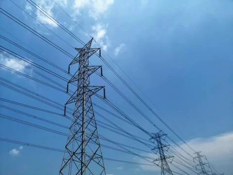 Low Angle View of High Voltage Tower and Power Lines Against Blue Cloudy Sky Stock Photos