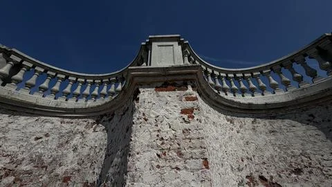 Low angle view of a historic curved brick wall with peeling white plaster and Stock Photos