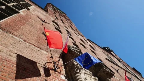 Low angle view of historic red brick building facade with flying flags unde.. Stock Footage 337524299