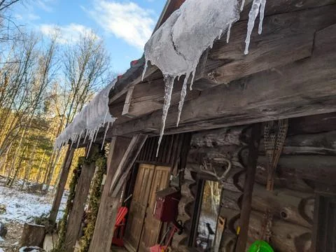 Low Angle View of Icicles on Rustic Log Cabin in Winter Fotos Stock