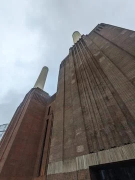 Low-angle view of the iconic Battersea Power Stations brick facade and chimneys Stock Photos