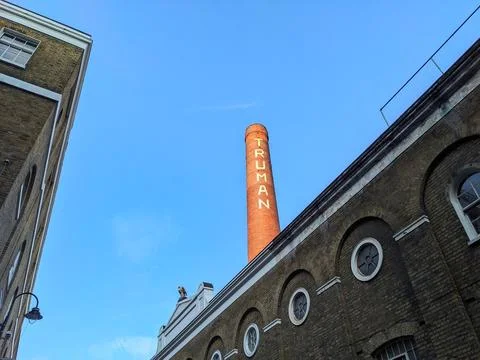 Low angle view of the iconic Truman Brewery chimney against a clear blue sky in Stock Photos