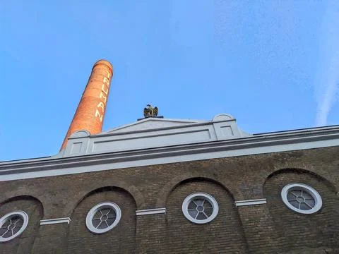 Low angle view of the iconic Truman Brewery chimney and eagle sculpture against Stock Photos